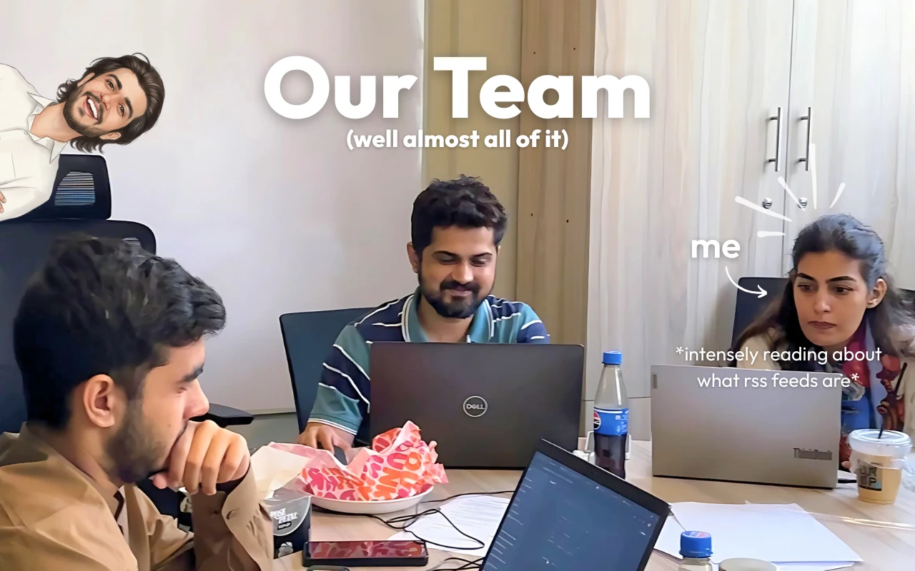 Three team members working on laptops at a shared desk, with a humorous cartoon of another colleague peeking over the chair.